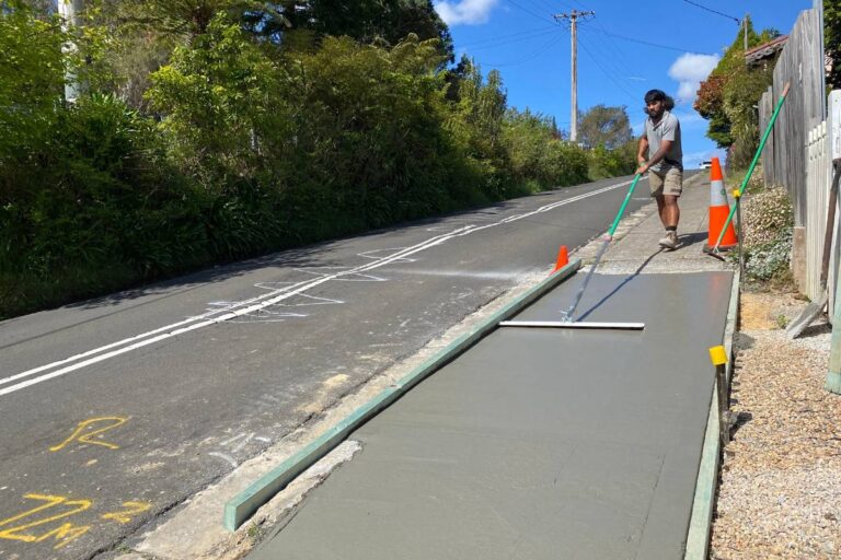 Laser Concrete team finishing a new concrete footpath beside a road