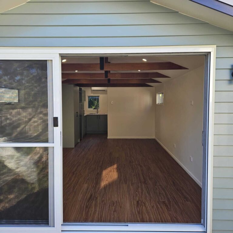 Interior of a converted garage with a kitchenette and timber-look floor