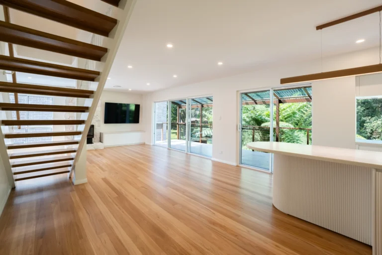 Open living space with timber stairs and floor-to-ceiling windows