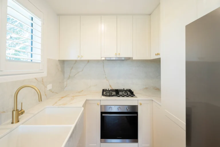 Granny flat kitchen with marble-look splashback and brass tapware in Springwood